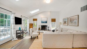 A spacious living room with a large sofa, a fireplace, and a television mounted on the wall.