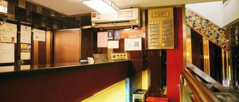 A reception area with a counter, a wall-mounted air conditioner, and a staircase with a colorful handrail.