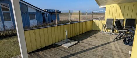 A covered patio with a view of a blue building and a yellow structure.
