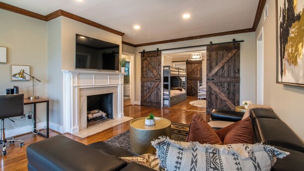 Un salon avec une cheminée, un canapé, une table basse et une porte coulissante de style grange donnant sur une chambre à coucher.