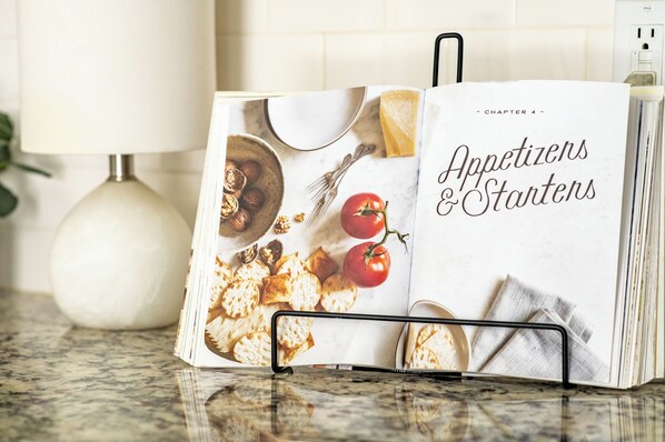 Un libro de cocina abierto sobre una encimera, mostrando un capítulo sobre aperitivos y entrantes.