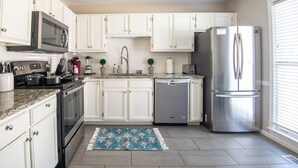 Una cocina moderna con armarios blancos, electrodomésticos de acero inoxidable y encimera de granito.