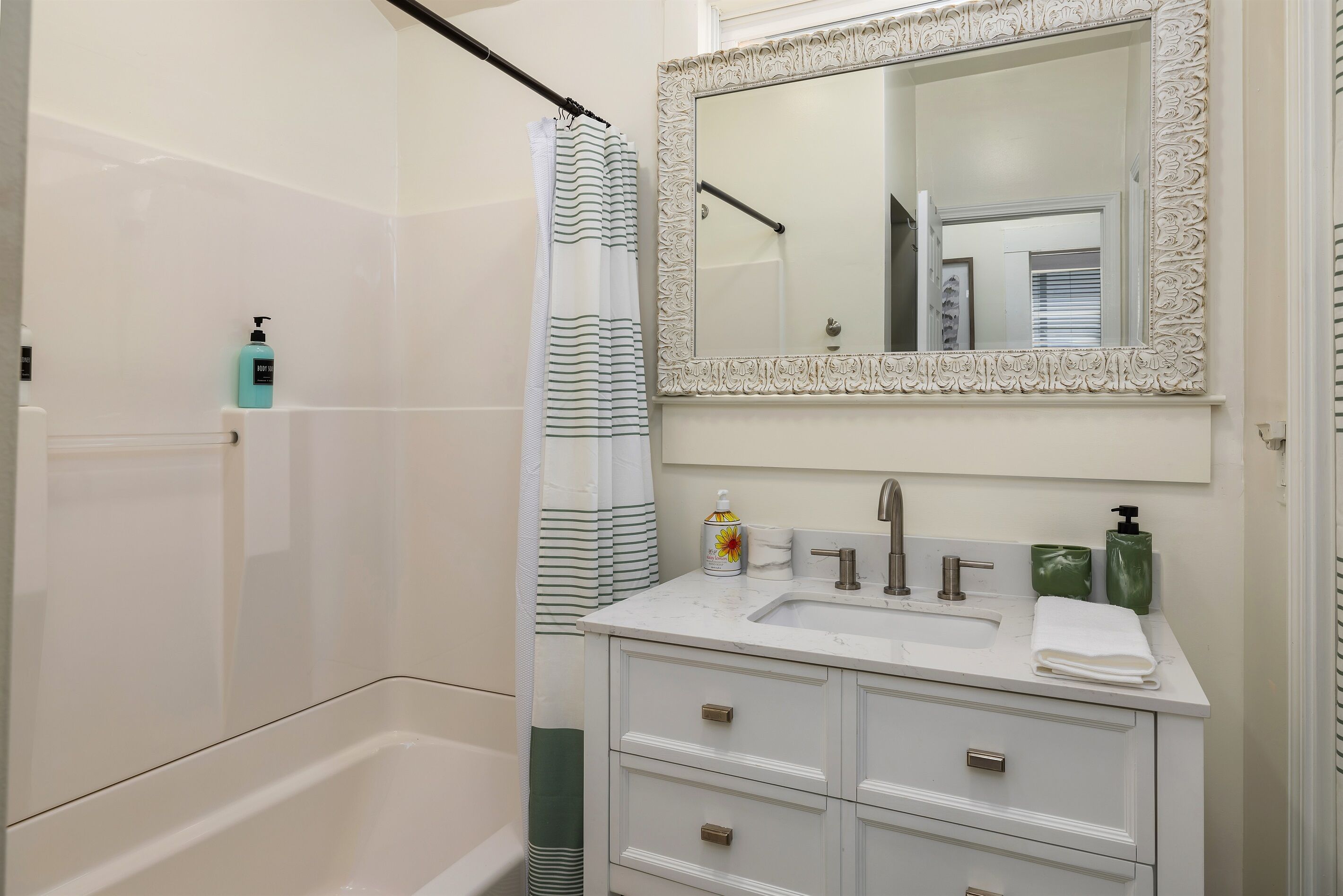 Un bagno con una vasca, un box doccia, un lavandino con specchio e articoli da toilette.