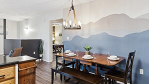 A dining area with a wooden table set for four, a bench, and a chandelier.