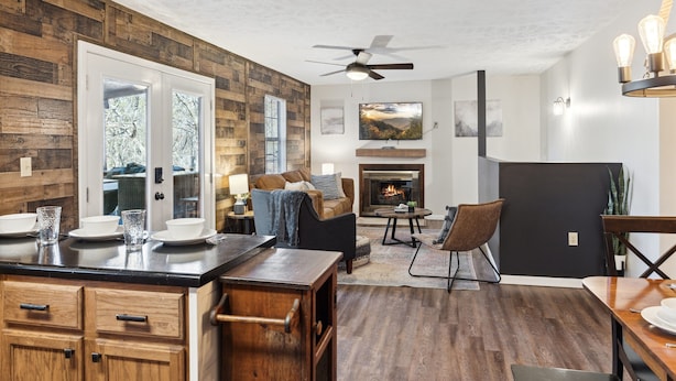 A modern living room with a fireplace, wooden paneling, and a dining area with a black table and chairs.