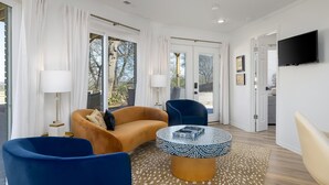 A modern living room with a sofa, chairs, a coffee table, and a TV. - The Hobbit House - City Views/Deck & Patio/Firepit (birmingham)