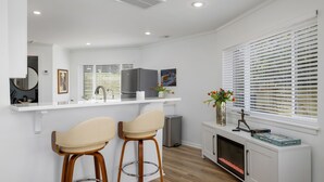 A modern kitchen with white cabinetry, a built-in oven, and a small dining area with two stools. - The Hobbit House - City Views/Deck & Patio/Firepit (birmingham)