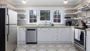 Una cocina moderna con armarios blancos, lavavajillas, estufa y pileta.