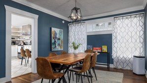 Un comedor con una mesa de madera, seis sillas, un florero con una planta y una lámpara colgante.