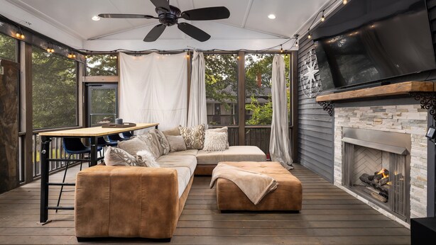 A covered outdoor living area with a sectional sofa, ottoman, ceiling fan, and fireplace. - Warren Home: A Glimpse into BHAM's Rich Past (birmingham)