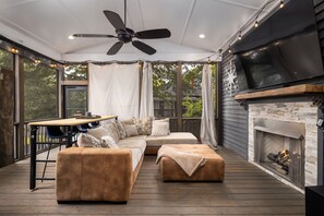 A covered outdoor living area with a sectional sofa, ottoman, ceiling fan, and fireplace. - Warren Home: A Glimpse into BHAM's Rich Past (birmingham)