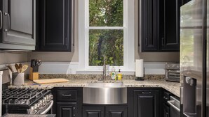 A modern kitchen with dark cabinets, a stainless steel sink, a gas stove, and a built-in oven. - Warren Home: A Glimpse into BHAM's Rich Past (birmingham)