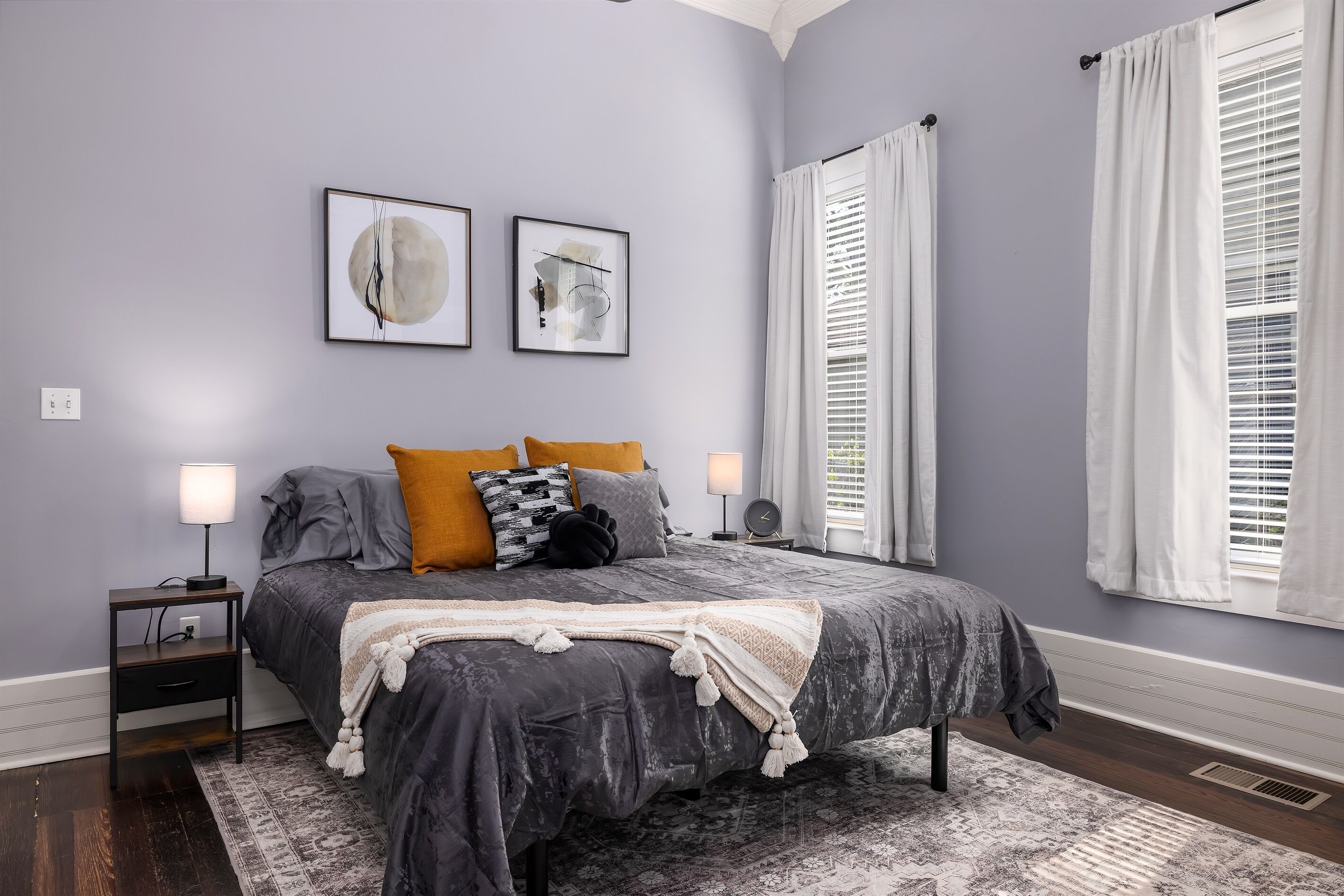 Une chambre à coucher avec un lit, des tables de chevet, un tapis et deux tableaux encadrés accrochés au mur.