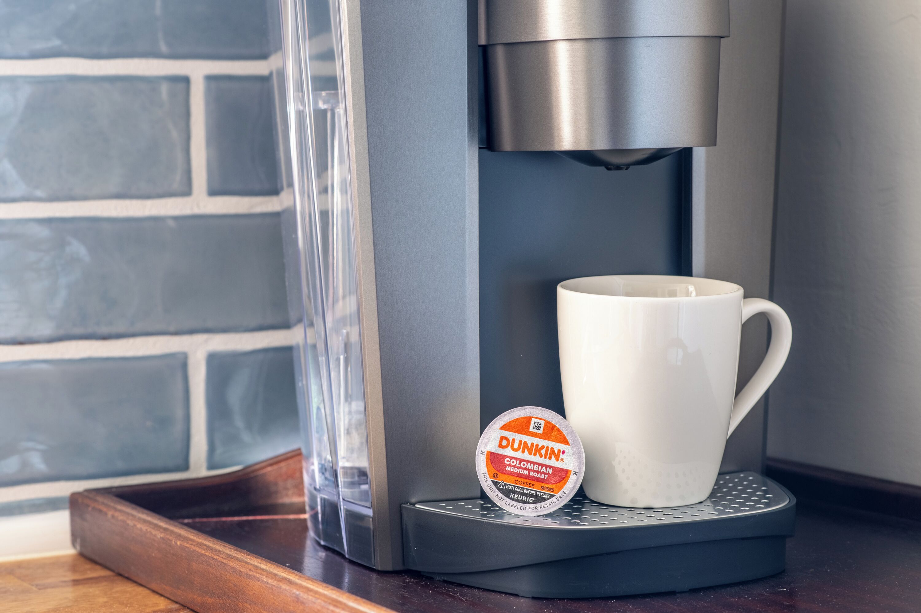 A coffee machine with a white mug and a Dunkin' coffee pod.