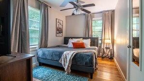 A bedroom with a bed, a ceiling fan, a TV, and a window with curtains. - Vulcan View- Groups/King Beds/Free Parking/2 Units (Birmingham)