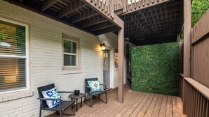 A wooden deck with two chairs and a table, a white brick wall, and a green hedge. - Vulcan View- Groups/King Beds/Free Parking/2 Units (Birmingham)