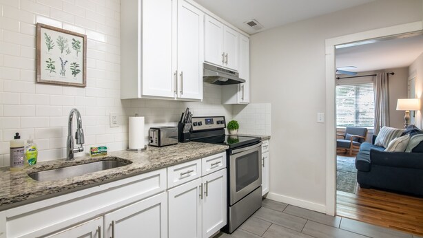 A modern kitchen with white cabinets, a granite countertop, a stainless steel oven, and a sink. - Vulcan View- Groups/King Beds/Free Parking/2 Units (Birmingham)