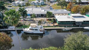 Un puerto deportivo con un yate blanco amarrado, rodeado de edificios residenciales y palmeras.