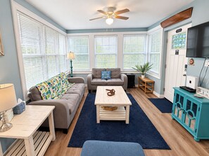 A living room with a sofa, a coffee table, a television, and a ceiling fan.