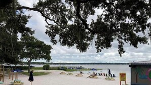 Une plage équipée de tables de pique-nique, de parasols et d’un panneau indiquant : « Bienvenue à Gator. »