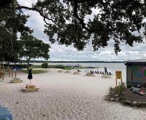 Ein Strand mit Picknicktischen, Sonnenschirmen und einem Schild, auf dem 'Welcome to Gator' steht.