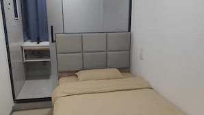 A small, single-bed room with a headboard, a bedside table, and a curtain. - Haojia Community Hotel (Zhengzhou Zhengdong New Area Branch) (Zhengzhou)