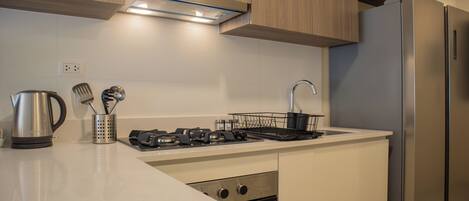 A modern kitchen with a stainless steel refrigerator, a built-in oven, and a gas stove.