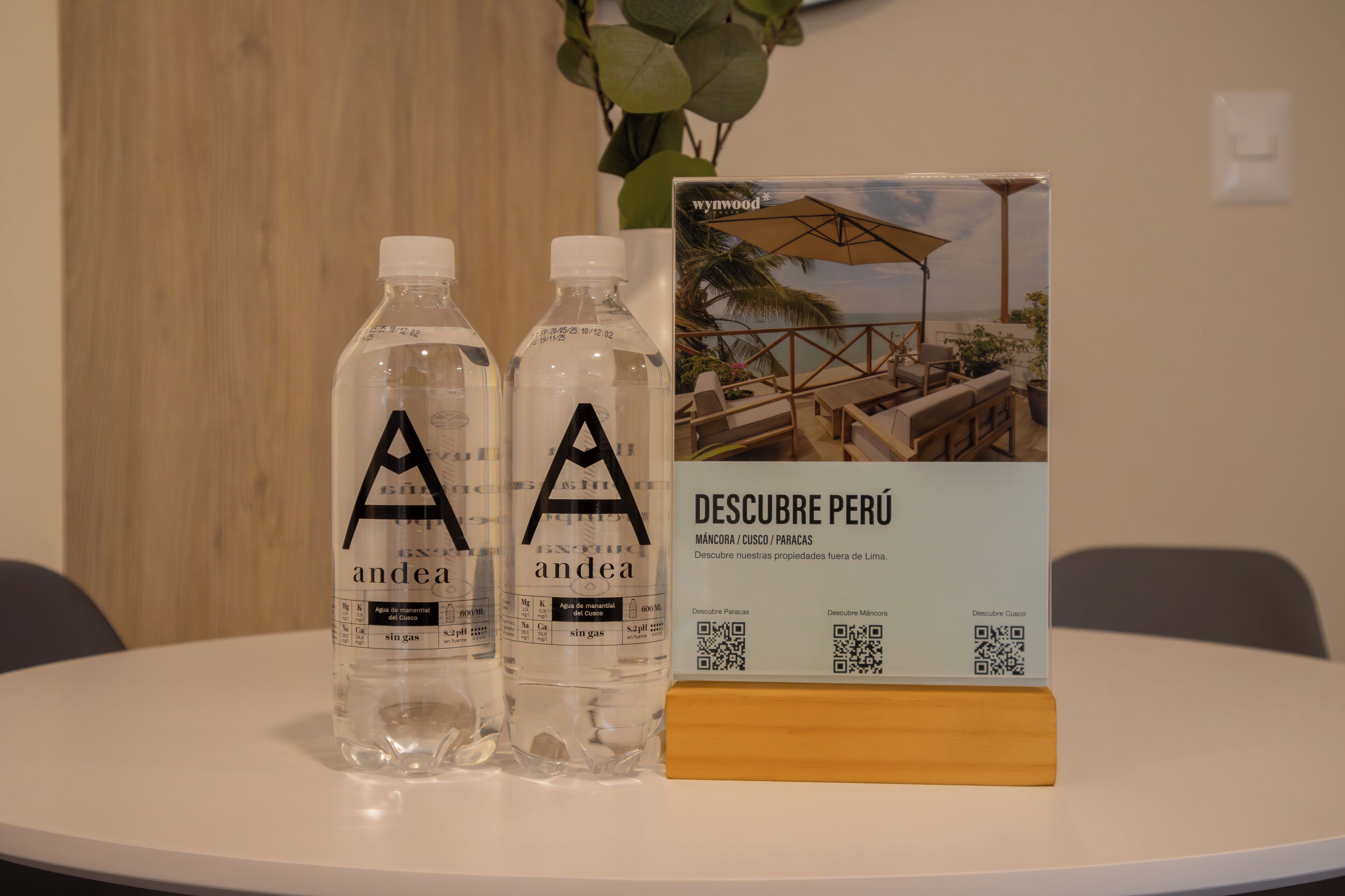Two bottles of water labeled 'andea' and a brochure titled 'DESCUBE PERÚ' on a table with a wooden block.