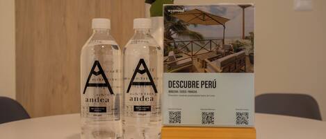 Two bottles of water labeled 'andea' and a brochure titled 'DESCUBE PERÚ' on a table with a wooden block.