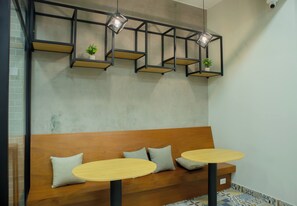 A modern interior with a wooden bench, two round tables, and geometric pendant lights with plants.