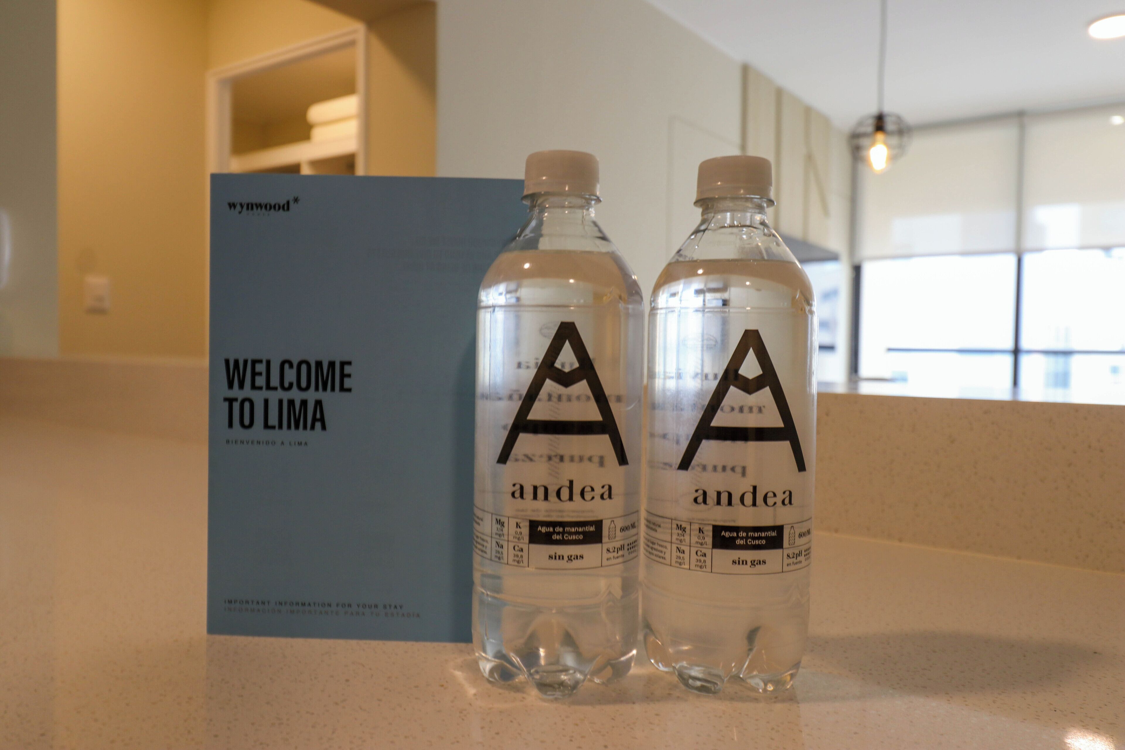 Two water bottles with labels and a welcome sign in a hotel lobby.