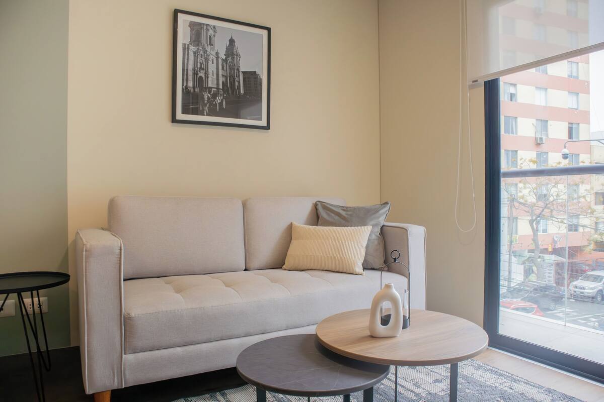 Un salon moderne avec un canapé, une petite table ronde et une photographie encadrée accrochée au mur.