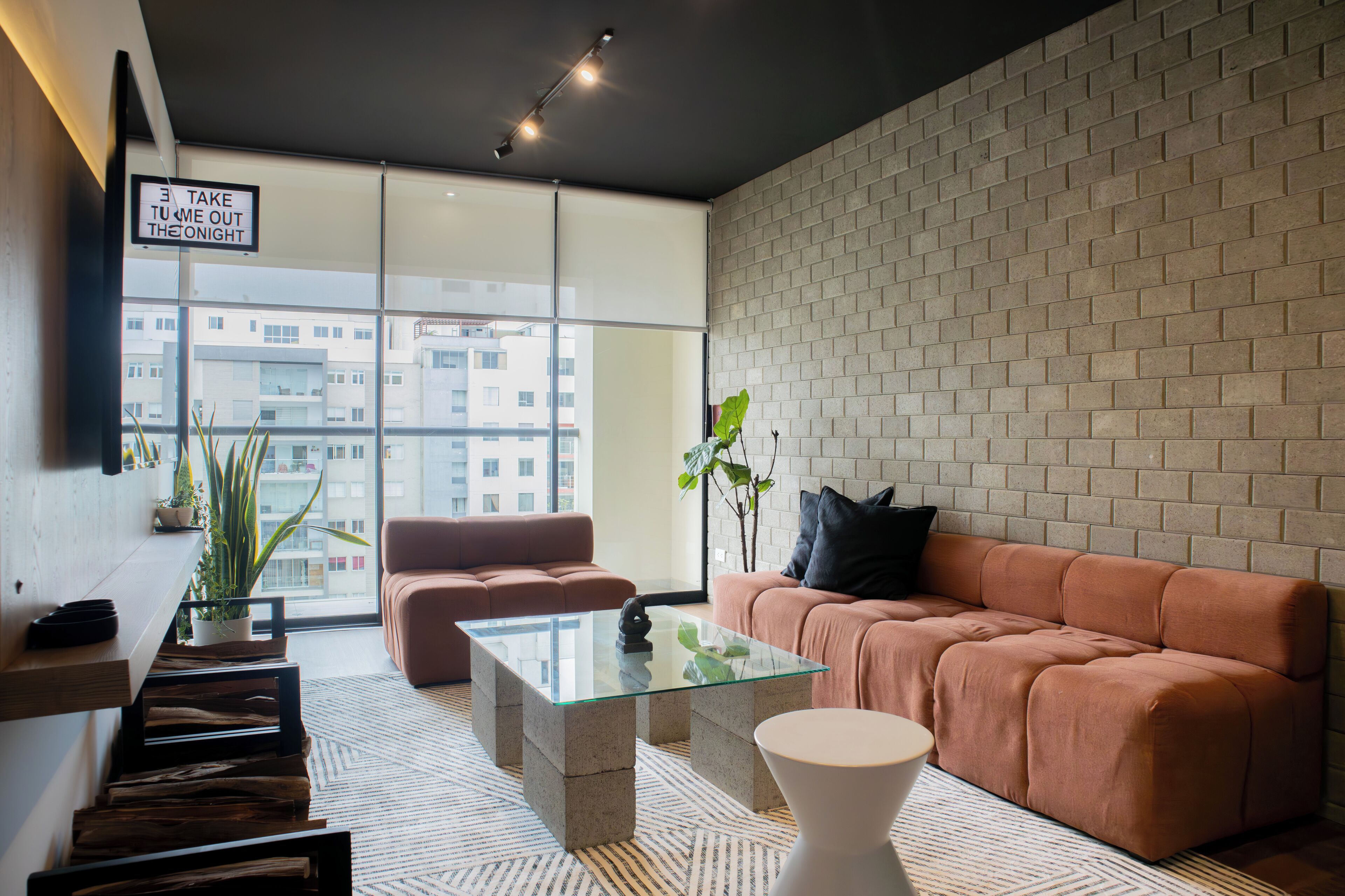 A modern living room with a sofa, a glass coffee table, and a potted plant.