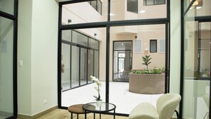 A modern interior with large glass windows, a round table with a vase of flowers, and a comfortable chair. - Treehouse by Wynwood House (Lima)