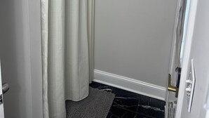 Un baño con cortina de ducha, una puerta con manija y un pequeño perchero.