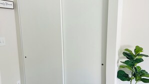 Una habitación con armario de puerta corredera, una planta en maceta y un plaid a rayas sobre un sofá.