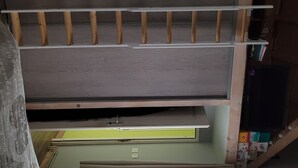 Una habitación con techo de madera, un ventilador de techo y una estantería con varios objetos.