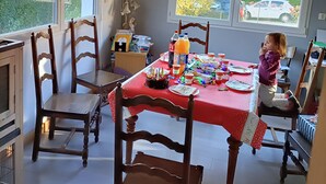 Un comedor con mantel rojo, sillas de madera y un cartel de cumpleaños.