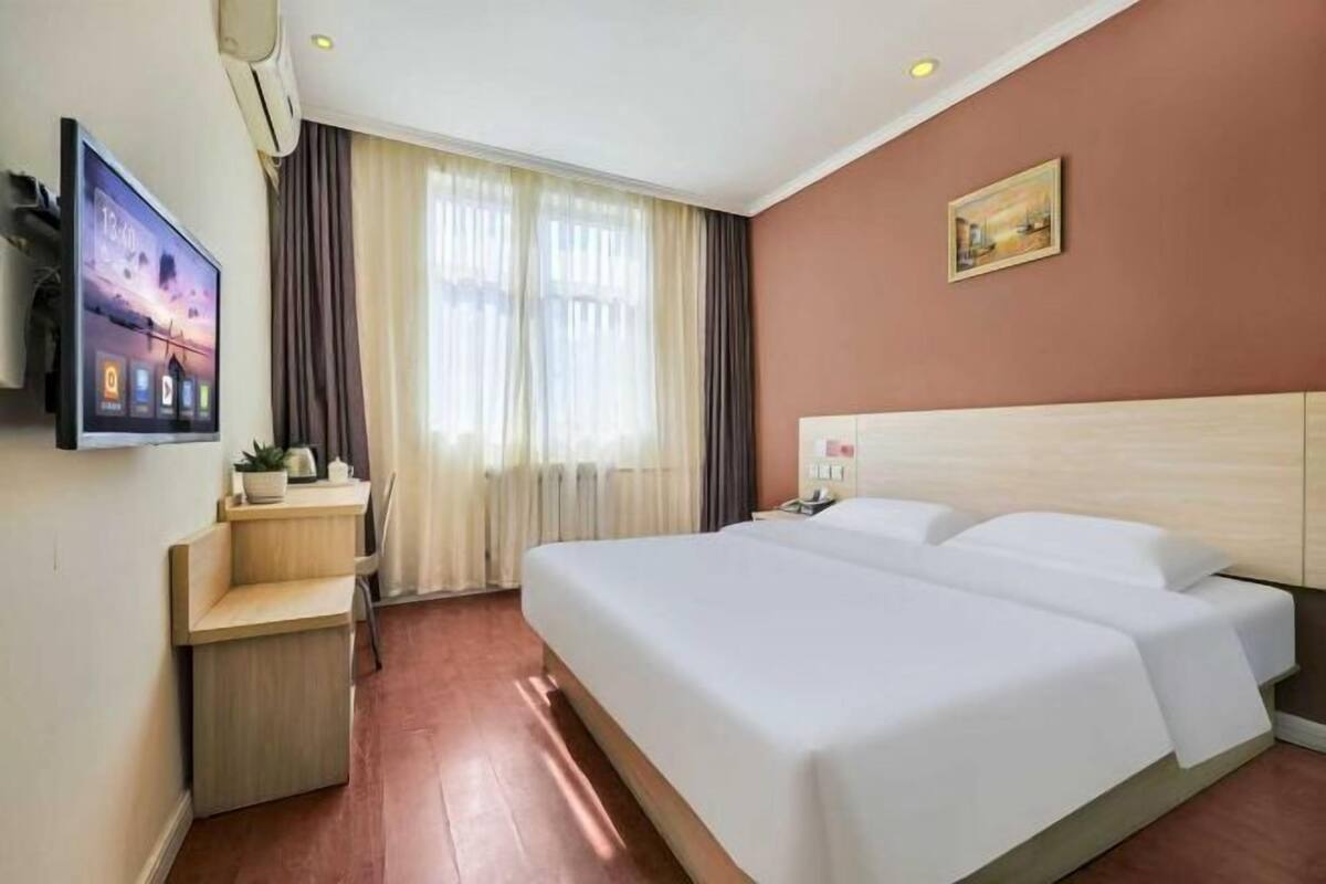 Ein Hotelzimmer mit Bett, Schreibtisch, Fernseher und einem Fenster mit Vorhängen.