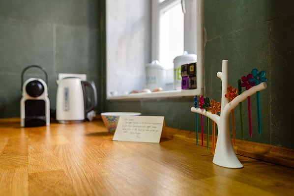 Una encimera de cocina con una cafetera, un hervidor de té y un florero decorativo.