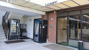 A vending area with a refrigerator and a vending machine, a staircase, and a lobby entrance. - Elkton Lodge - Newark - Elkton - University Gateway (Elkton)