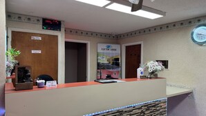 A hotel reception desk with a clock, a sign indicating check-out time, and a poster for Elkton Lodge. - Elkton Lodge - Newark - Elkton - University Gateway (Elkton)
