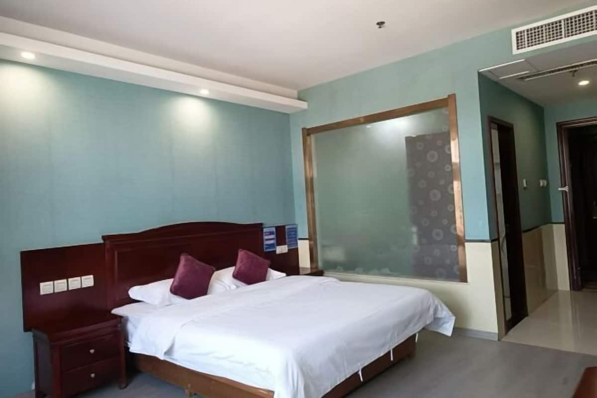 A hotel room with a bed, nightstand, and a mirror.