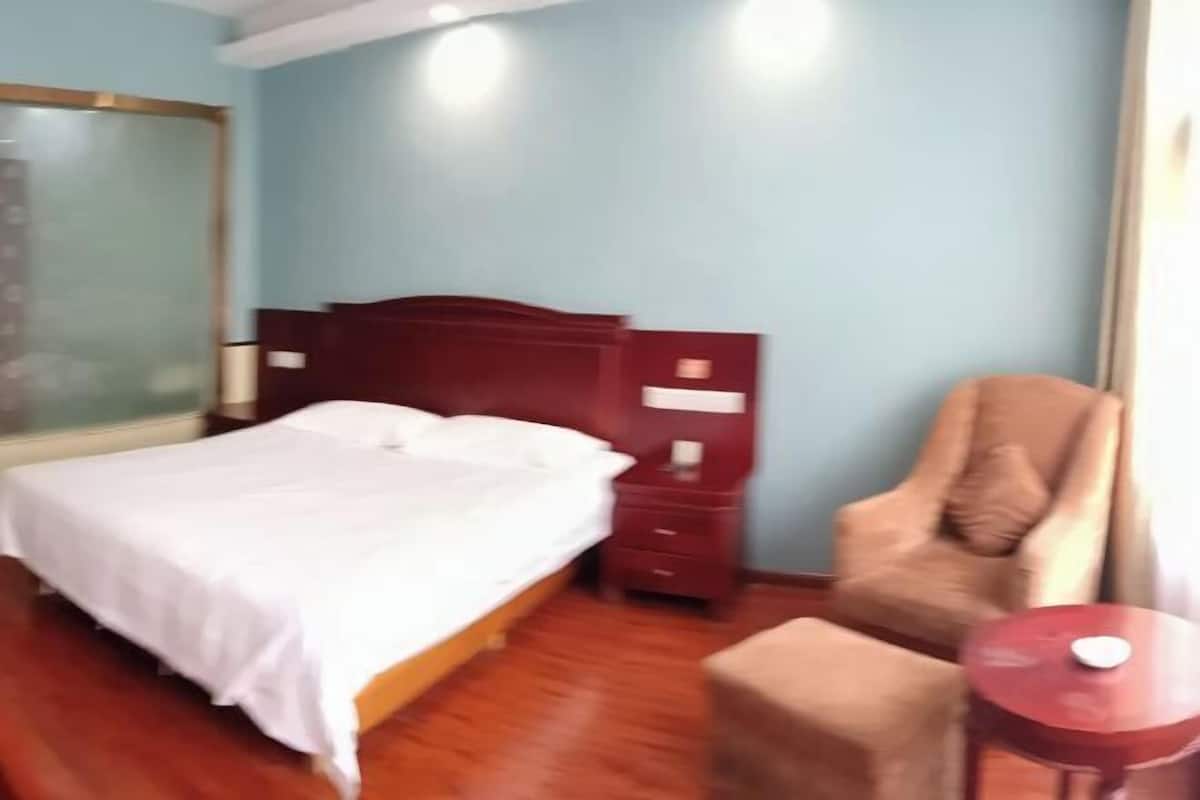 A hotel room with a bed, a chair, a small table, and a nightstand.