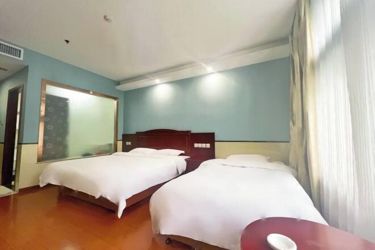 A hotel room with two beds, a wooden headboard, a mirror, and a red table.