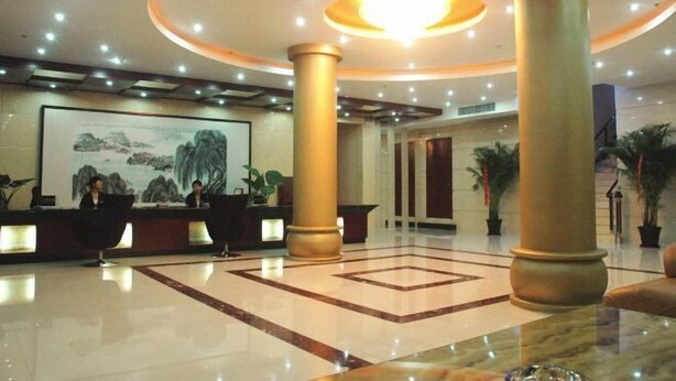 A hotel lobby with a reception desk, large columns, a chandelier, and a painting on the wall. - Zhongchen Hotel (Chizhou Nanhu Road) (Chizhou)