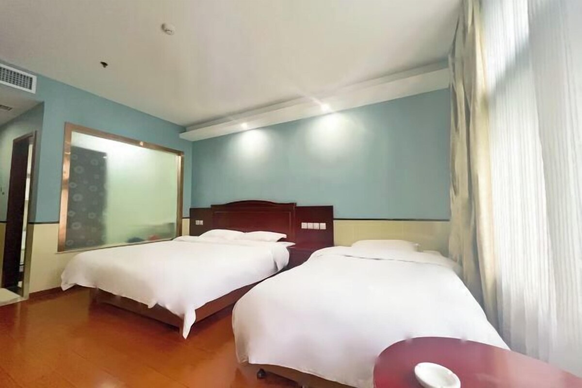 A hotel room with two beds, a wooden headboard, a large mirror, and a red table.