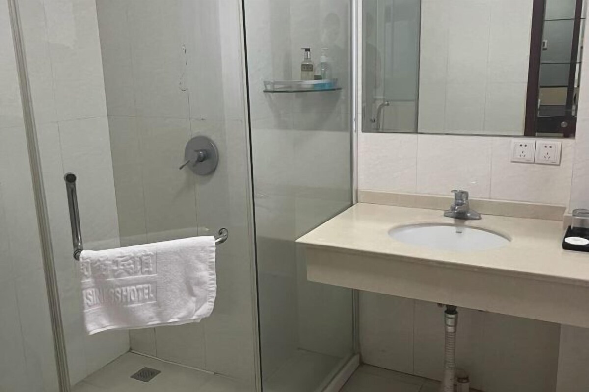 A bathroom with a glass shower enclosure, a white sink, and a mirror.