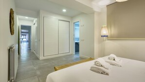 Une chambre d’hôtel comprenant un lit, une salle de bain et un couloir menant à une autre pièce.