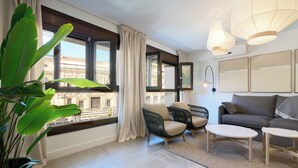 Un salon moderne comprenant un canapé, deux fauteuils, une table basse et une grande fenêtre avec des rideaux.